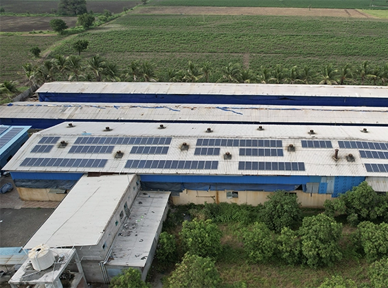 A sprawling industrial rooftop in Bharuch adorned with an array of solar panels, capturing the essence of Gujarat's shift towards sustainable energy, as pioneered by a leading solar power company.